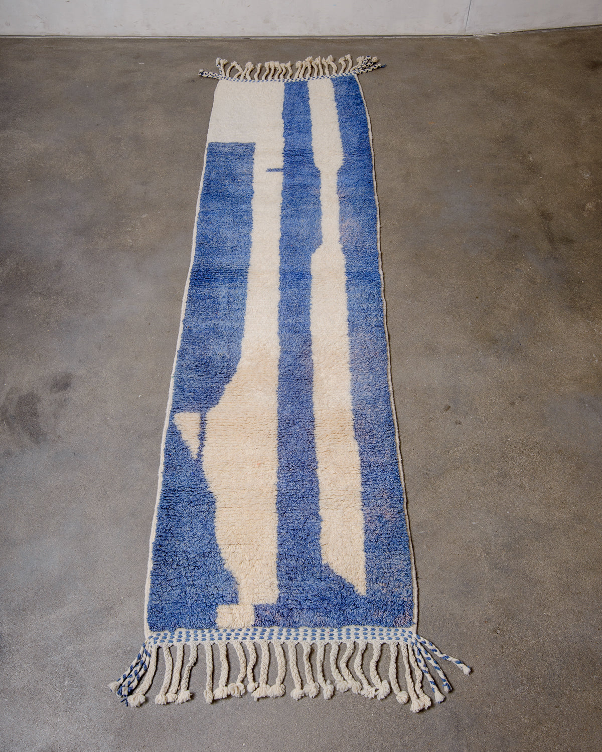 Berber runner rug made of blue and cream sheep's wool laying flat on floor.